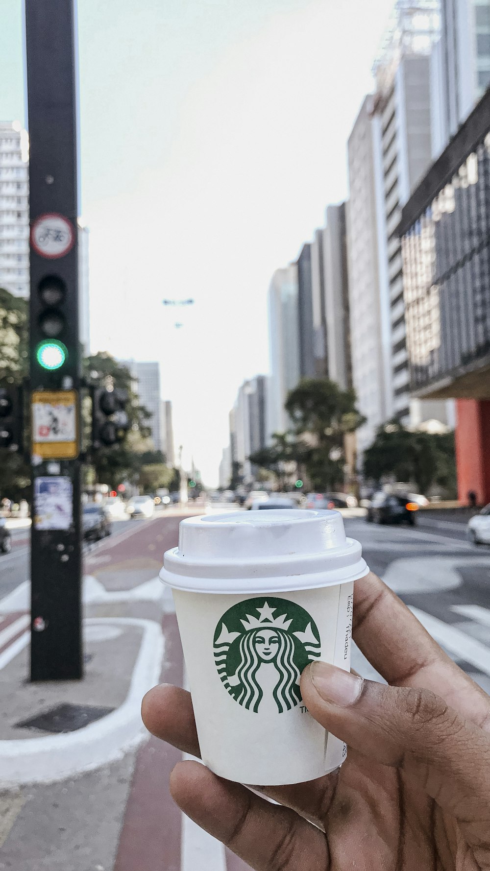 a hand holding a cup of starbucks coffee