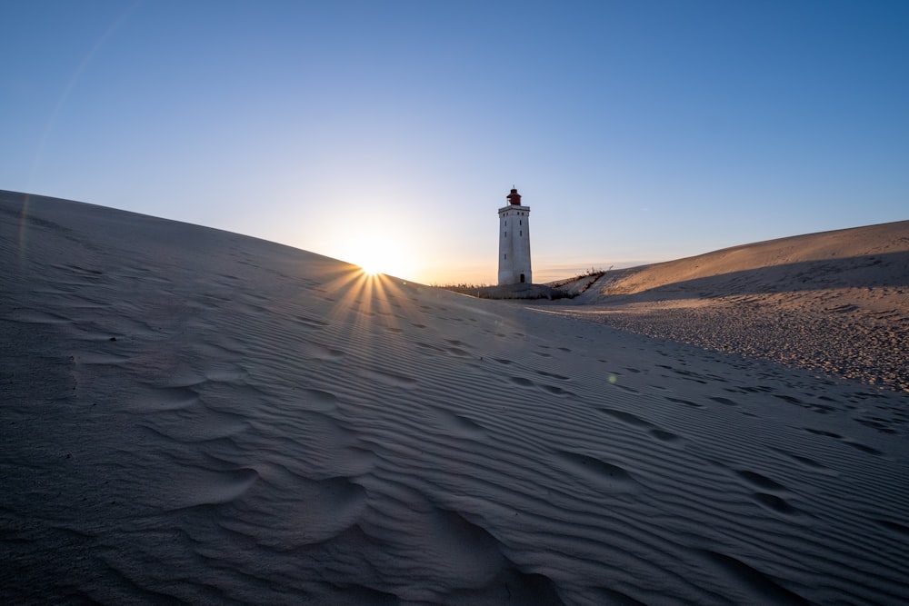 a lighthouse on top of a sand dune