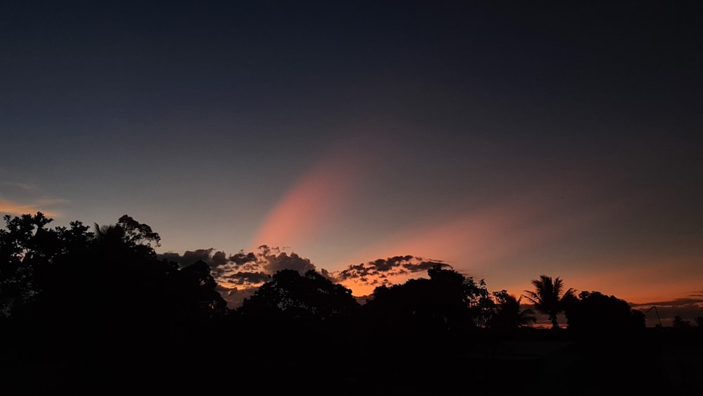 the sun is setting in the sky over the trees