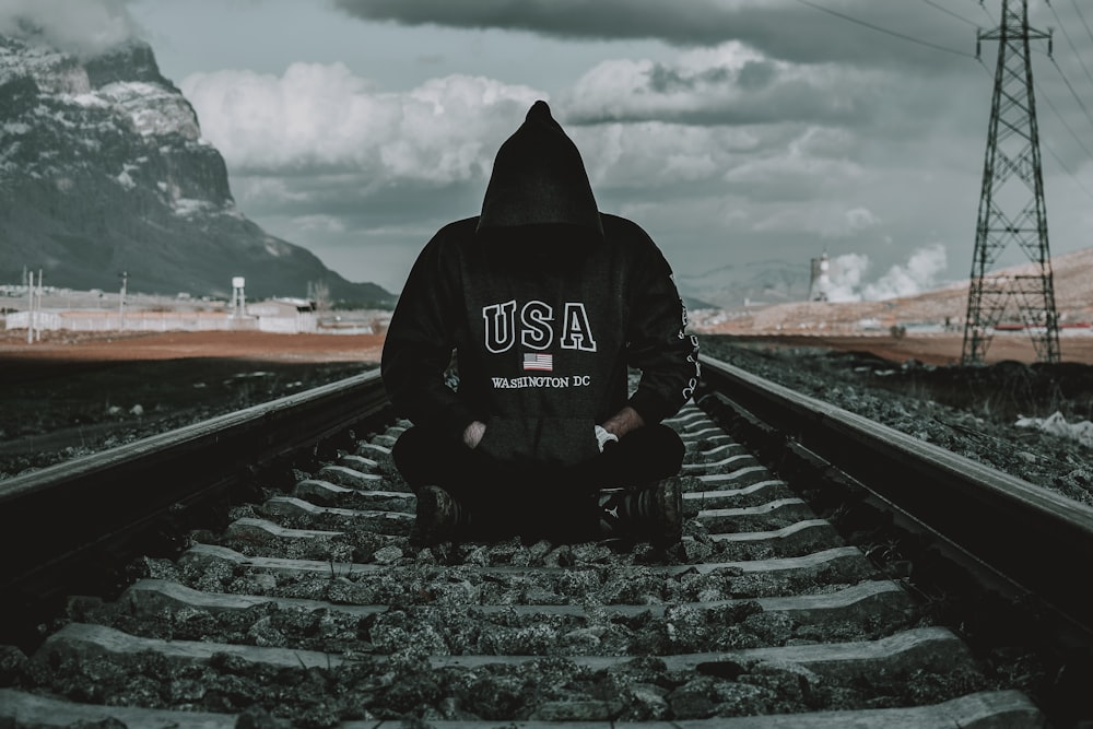 a person sitting on a train track with a mountain in the background