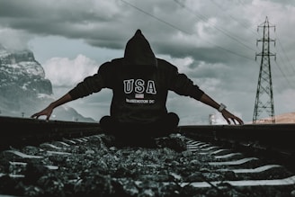 a person sitting on a train track with their arms outstretched