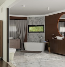A modern bathroom featuring a free-standing bathtub against a textured wall with a narrow horizontal window above it. There is a large circular mirror above a wooden vanity, complemented by a minimalist sink and faucet design. Neutral colors dominate the room, with accents of brown and gray. A soft rug is placed on the tiled floor, adding warmth to the space. Elegant drapes frame a side window, softening the overall atmosphere.