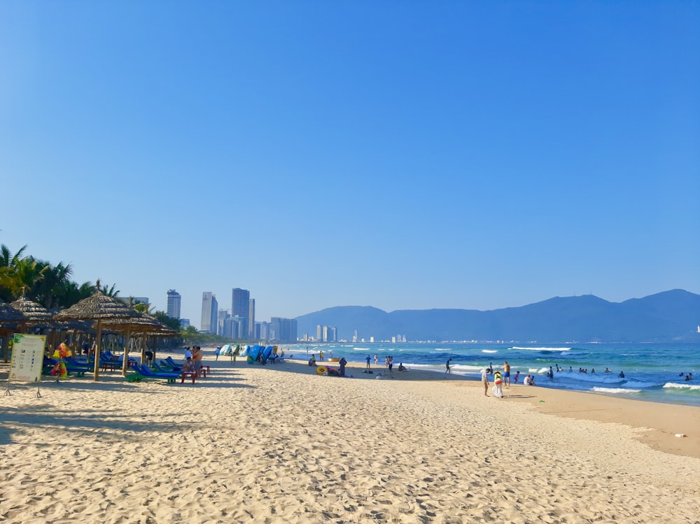 uma praia de areia com pessoas sobre ele e uma cidade ao fundo