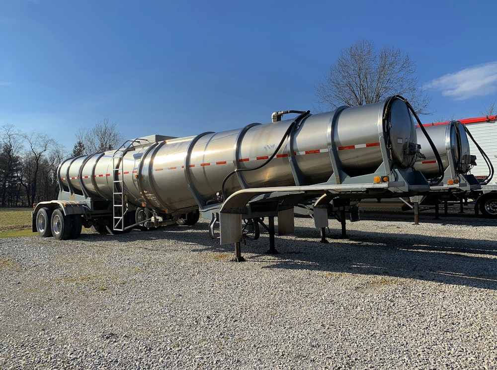 a large silver tanker truck parked in a gravel lot