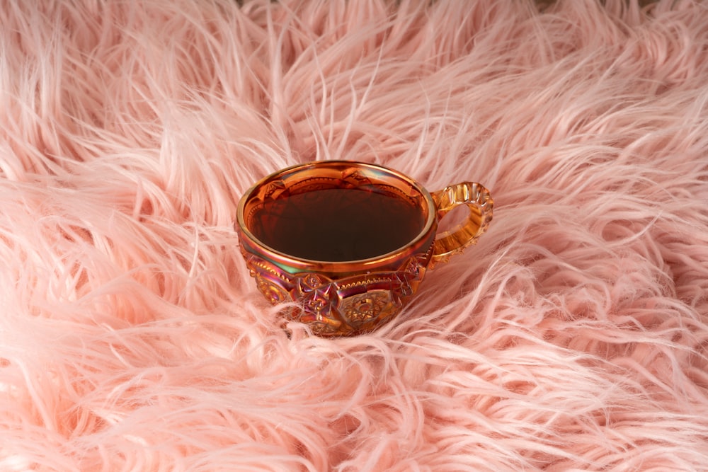 a cup of tea sitting on a fluffy pink blanket