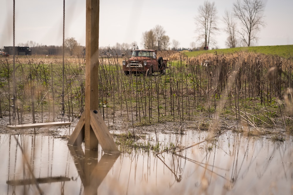 an old truck is parked in a swampy field