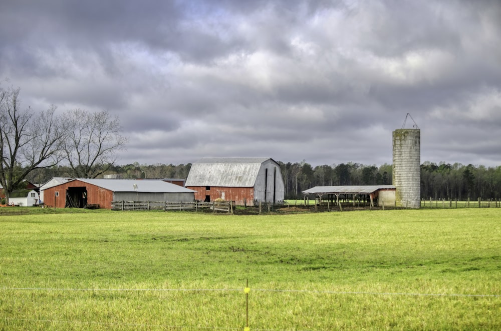 a farm with a barn and silo on a cloudy day