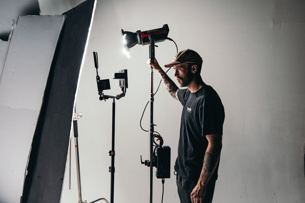 un homme debout devant une caméra et un équipement d’éclairage