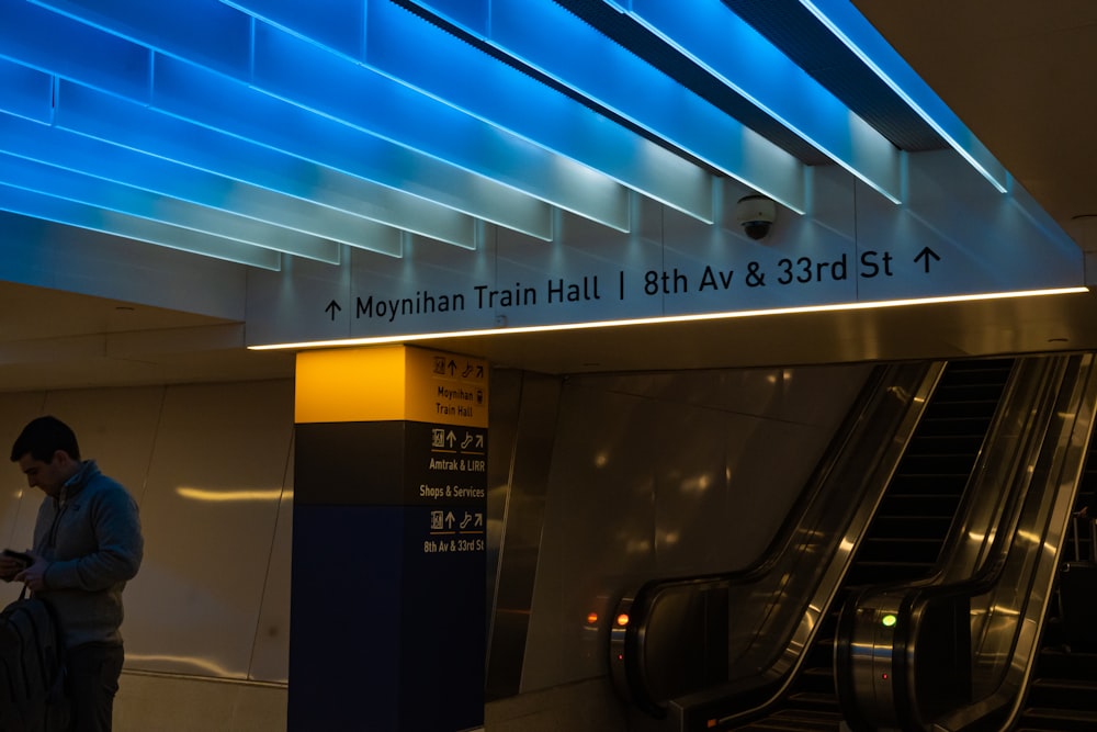 a man standing next to an escalator at a train station