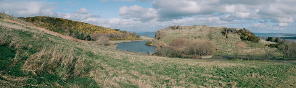 a grassy hill with a lake in the middle of it