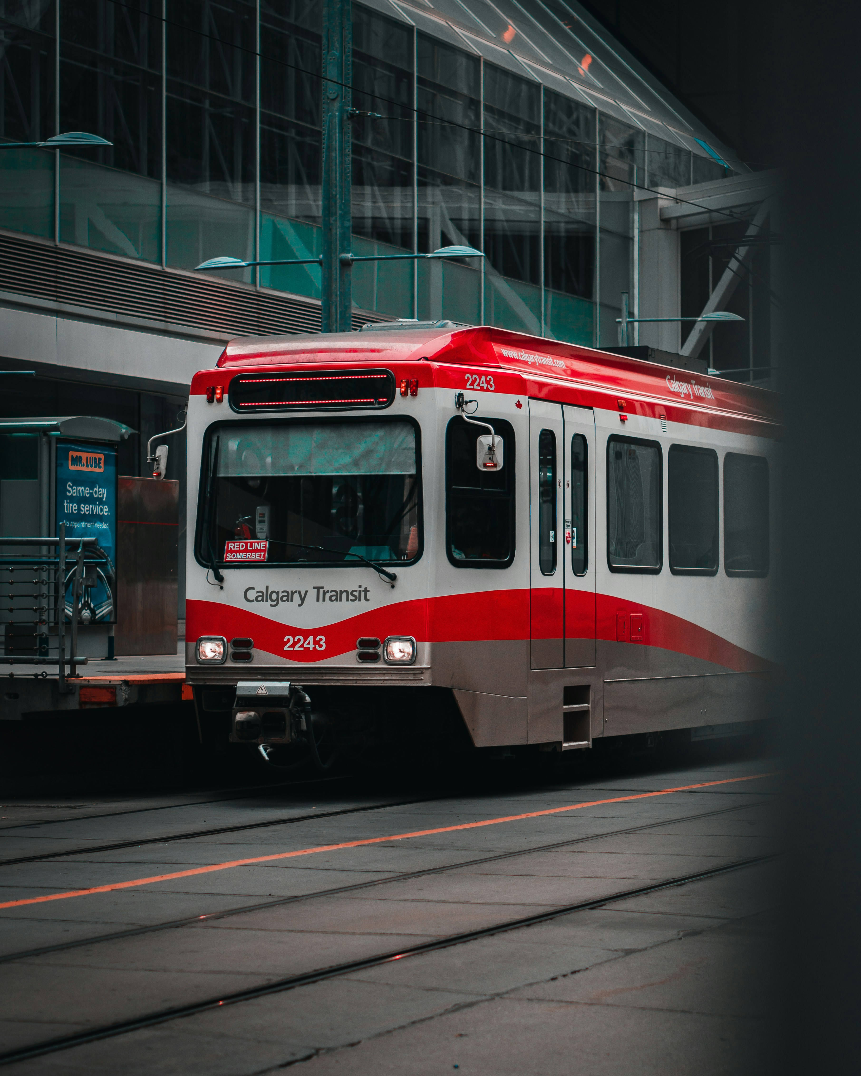 a red and white train traveling past a tall building
