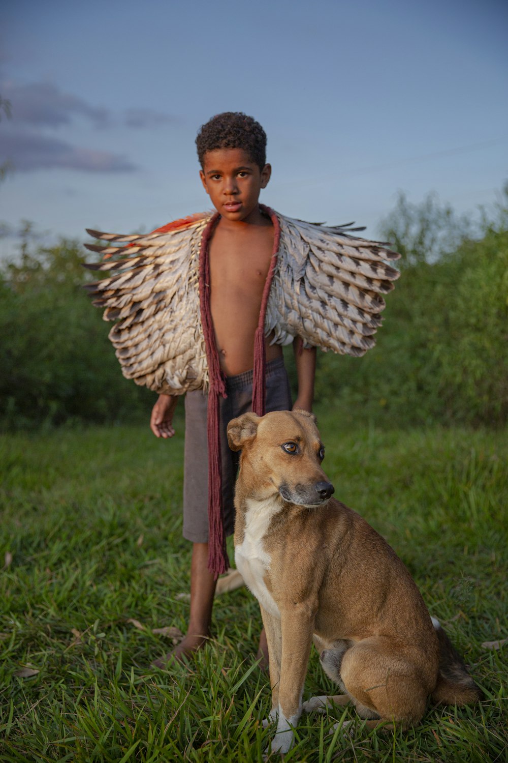 a young boy standing next to a dog in a field