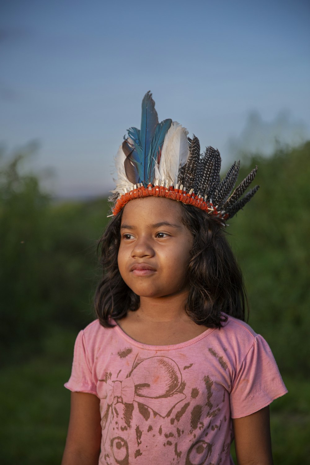 a young girl wearing a headdress made of feathers