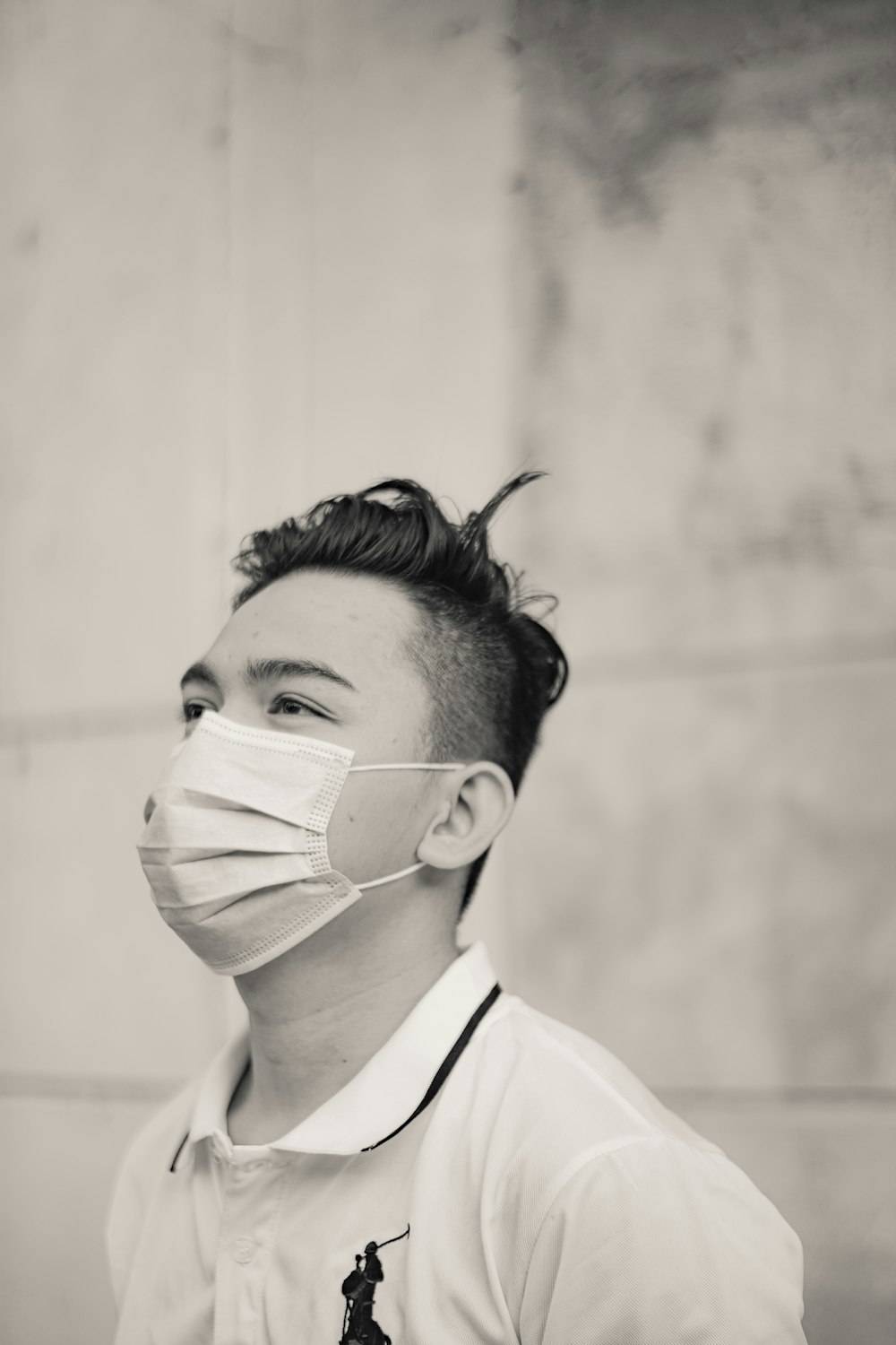 a man wearing a face mask while standing in front of a wall