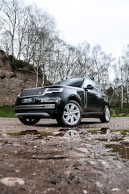 a black land rover parked on a muddy road