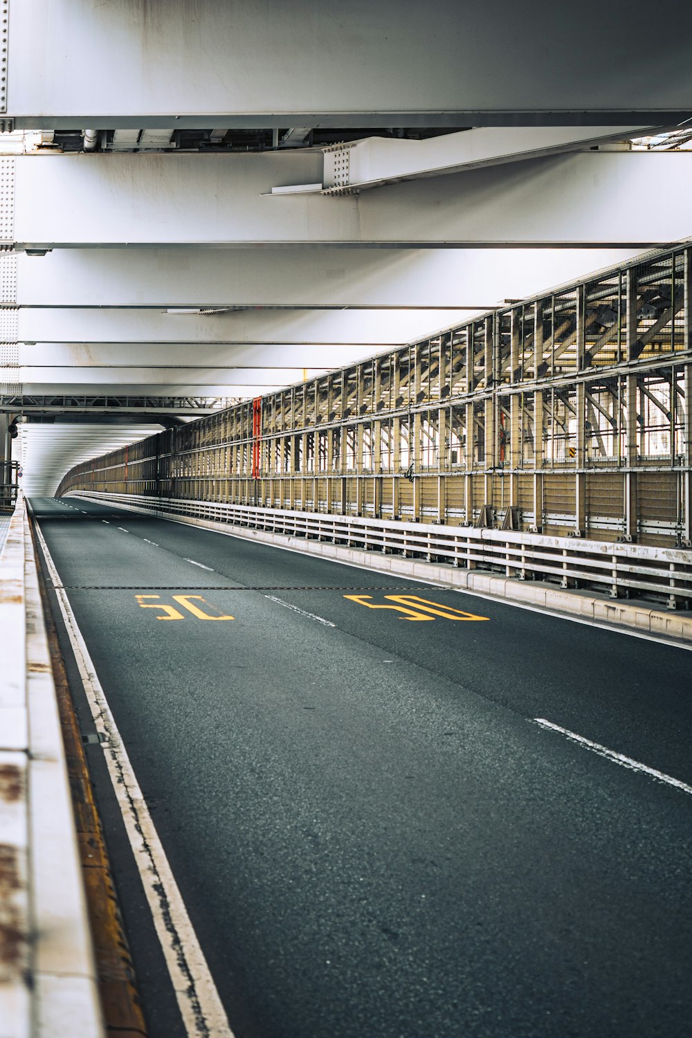 an empty street with a bridge in the background