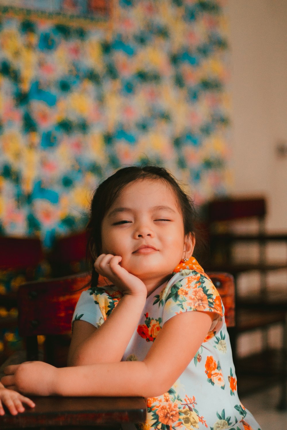 a little girl sitting at a table with her eyes closed