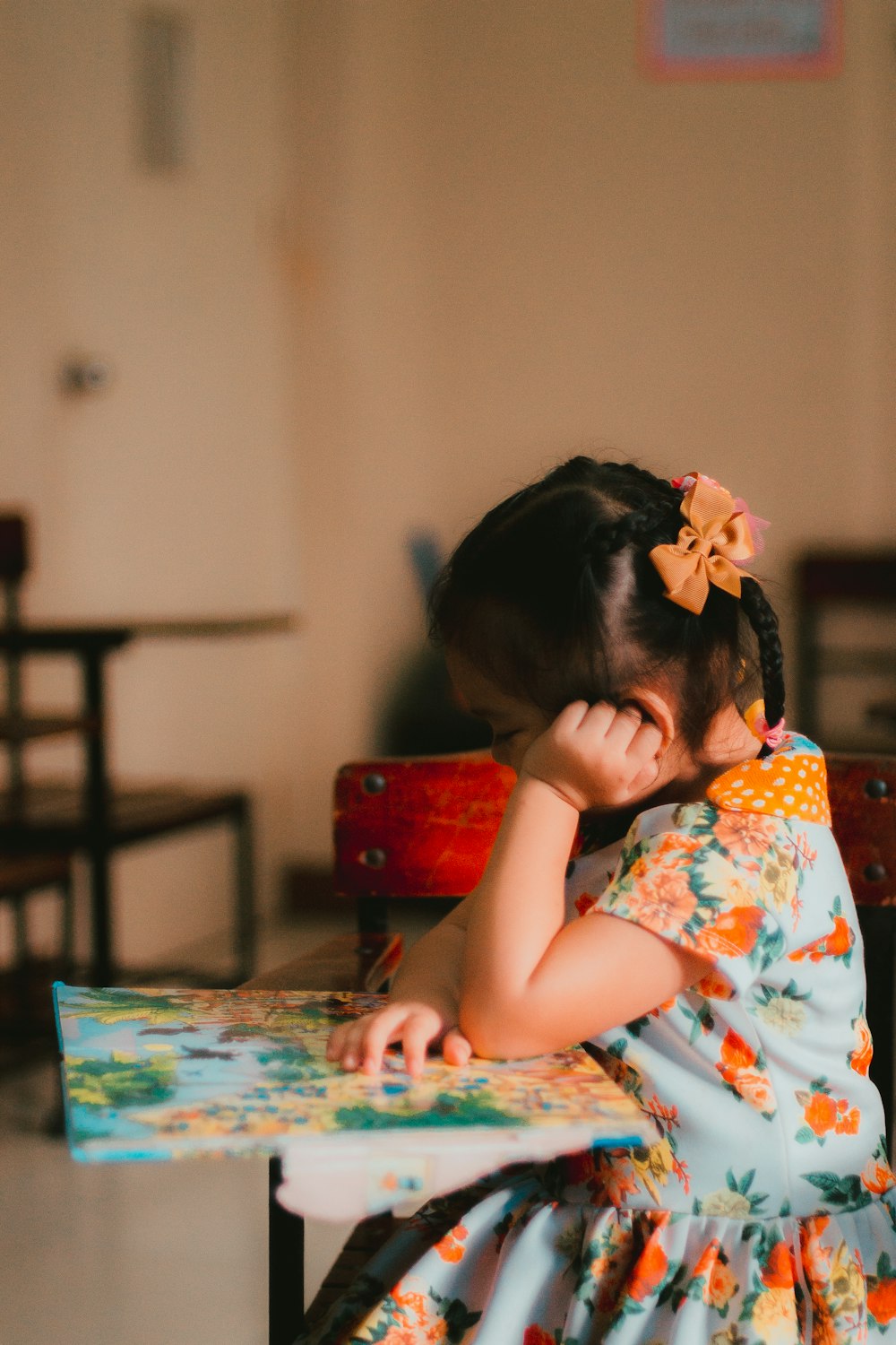 a little girl sitting at a table with a book