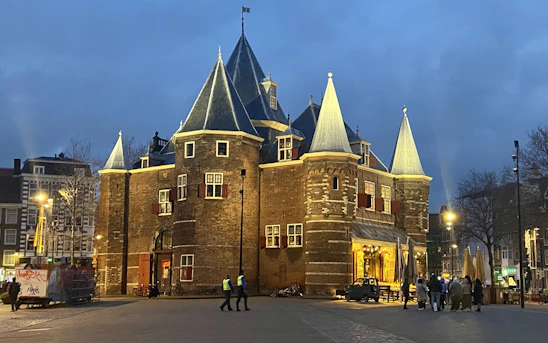 Historic brick lodge building with a warm evening glow and members gathered on the front steps.