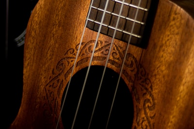 Close-up of an intricately carved ngombi harp resting on a wooden stand.