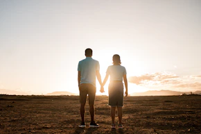 a man and a woman holding hands in the desert