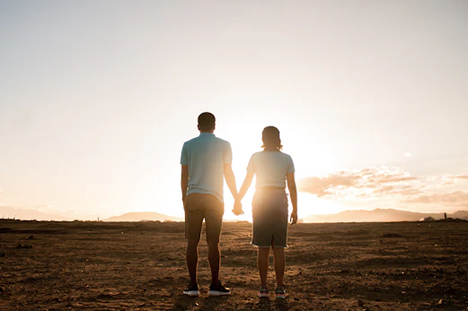 a man and a woman holding hands in the desert