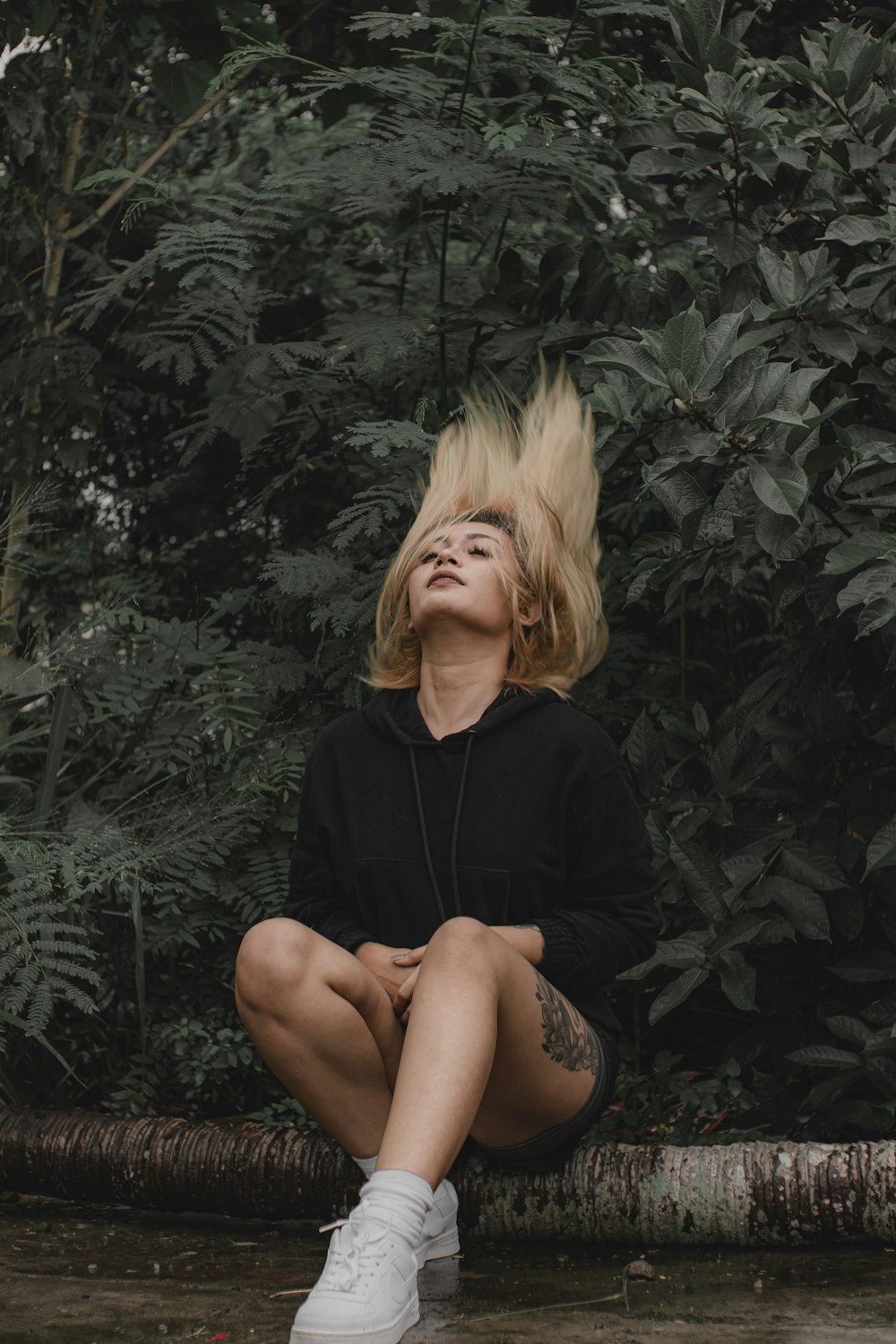 a woman with blonde hair sitting on a log