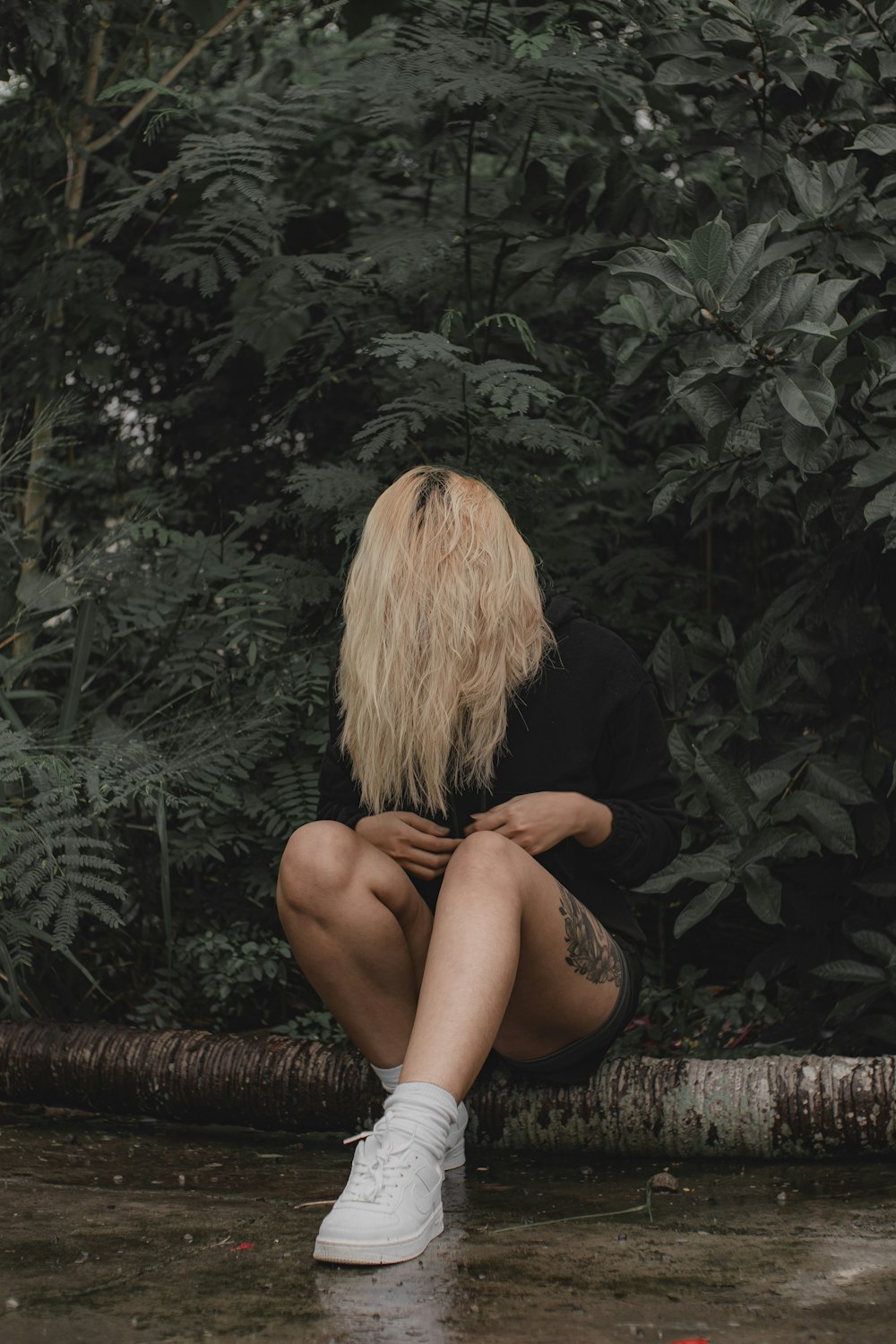 a woman sitting on a log in a forest