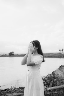 a woman in a white dress standing next to a body of water