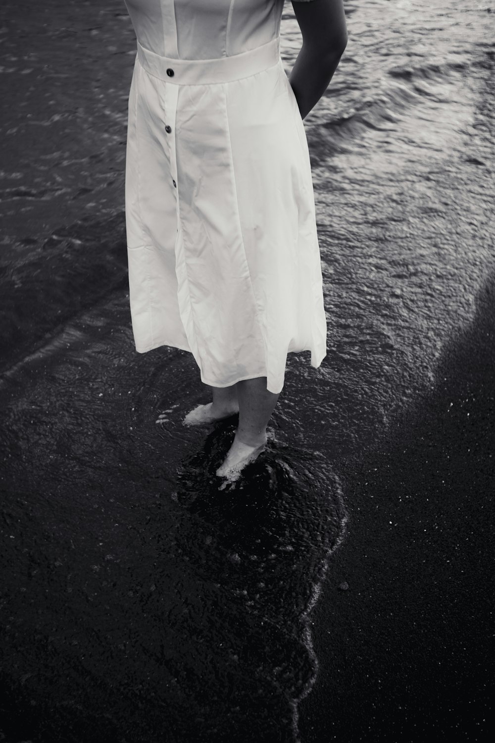 a woman in a white dress standing on a beach