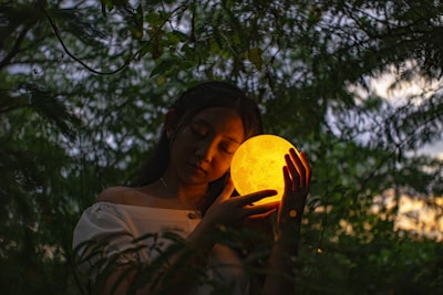 a woman holding a glowing yellow ball in her hands