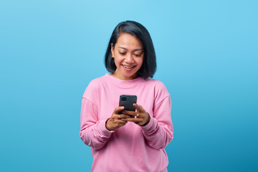a woman in a pink shirt looking at her cell phone