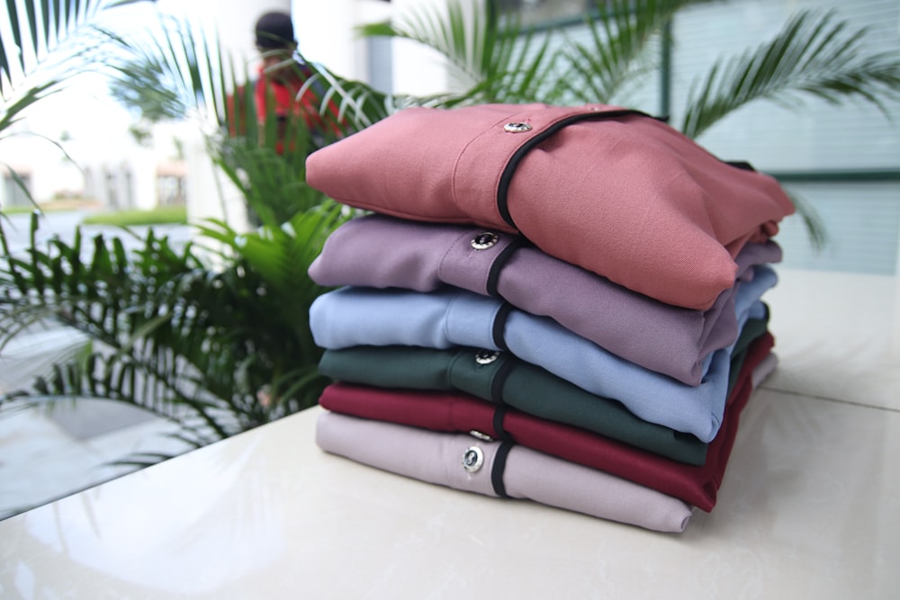 a stack of folded shirts sitting on top of a table