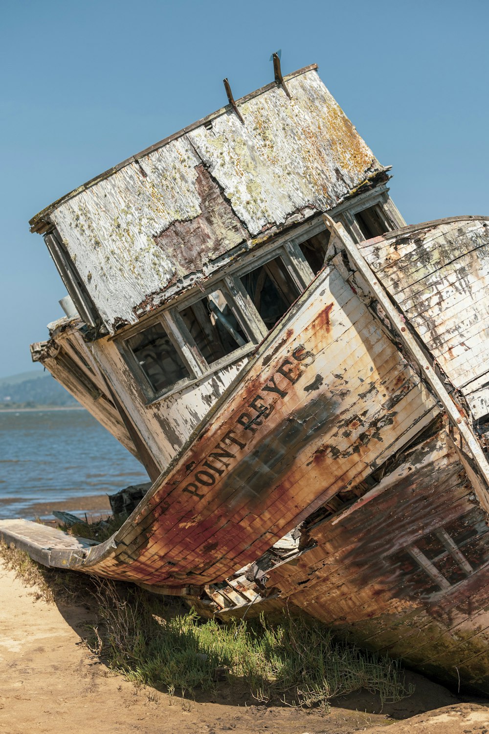 a rusted boat sitting on top of a sandy beach