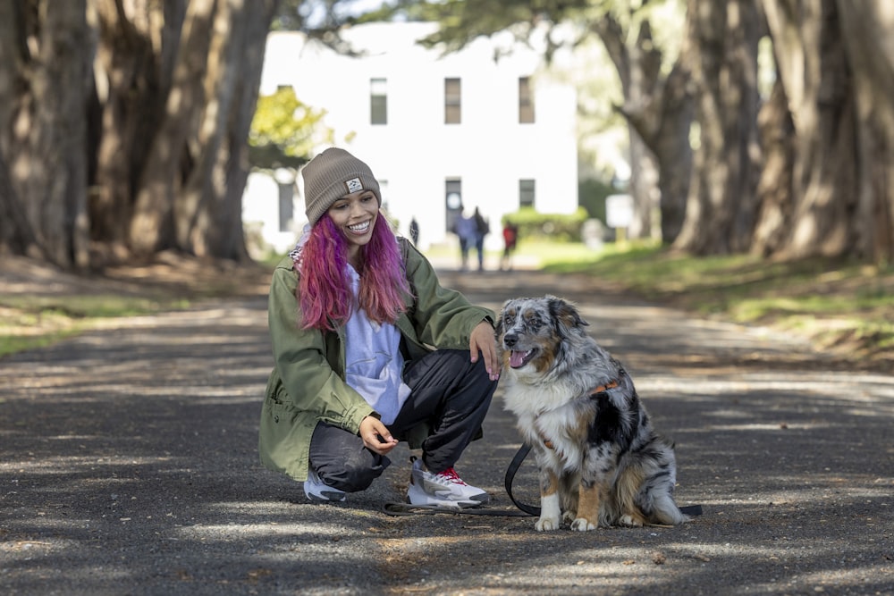 a woman sitting next to a dog on a road