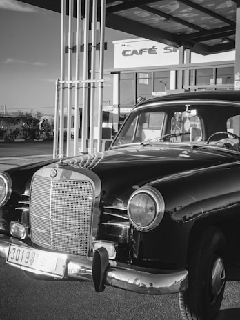The car parked beside a modern cafe, highlighting its unique design in an active urban setting.