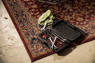 a tool box with tools inside of it on a rug
