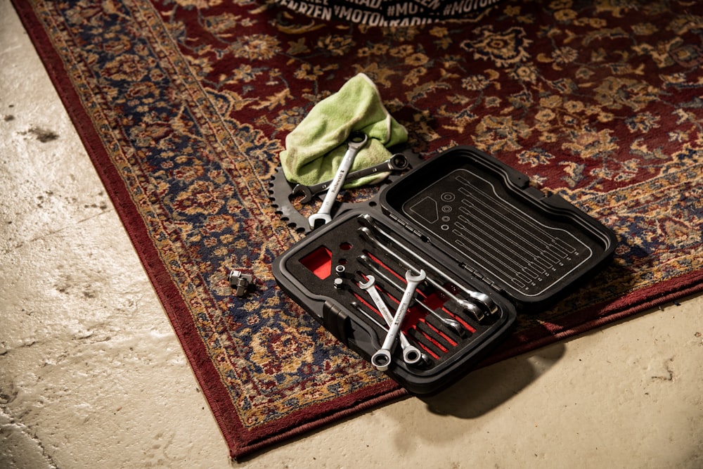 una caja de herramientas con herramientas dentro de ella en una alfombra