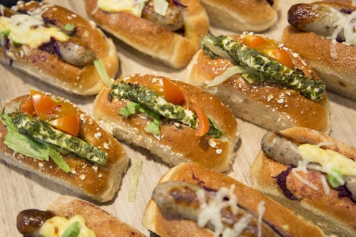a wooden table topped with lots of hot dogs covered in toppings