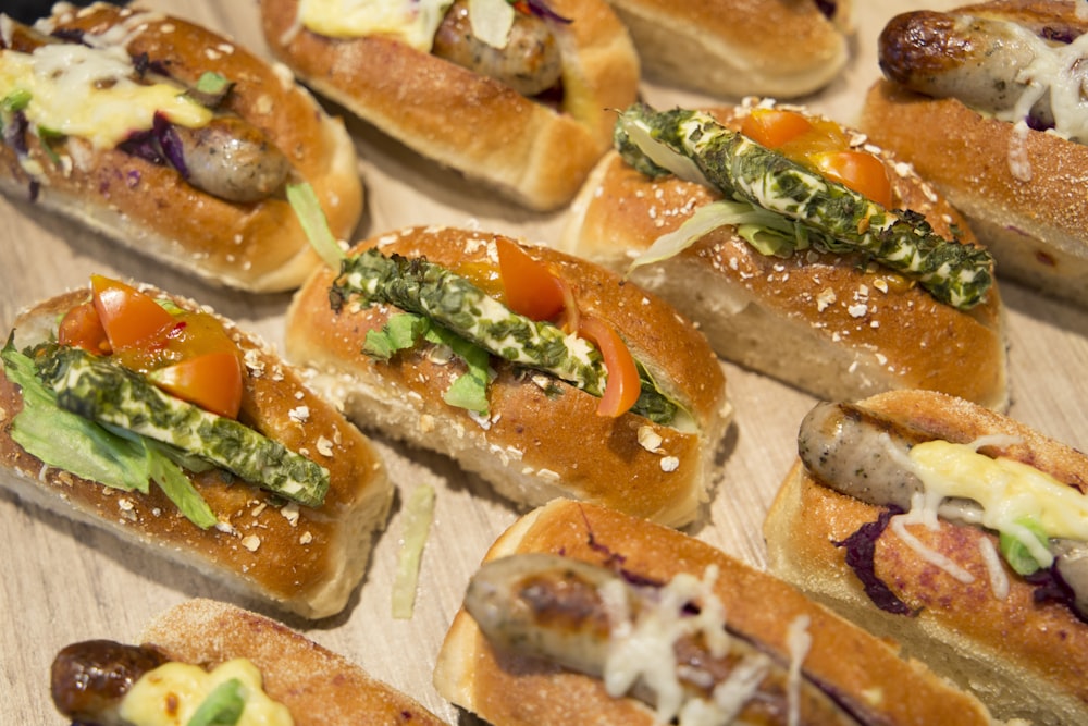 a wooden table topped with lots of hot dogs covered in toppings