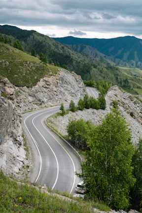 A winding mountain road with lush green forests on either side.