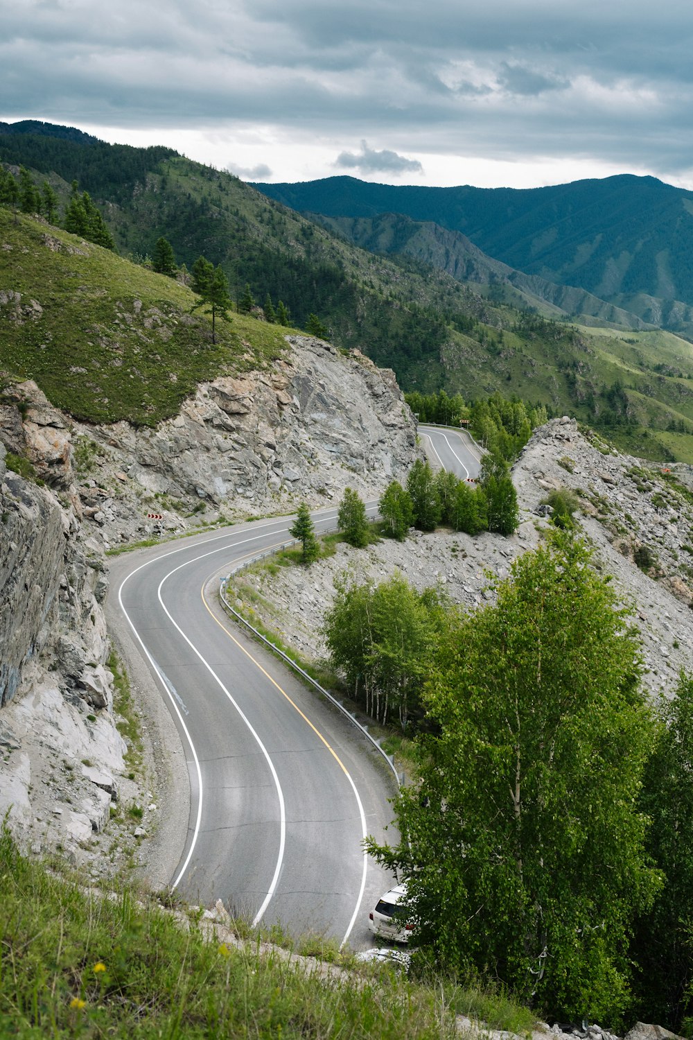 a winding road in the mountains on a cloudy day