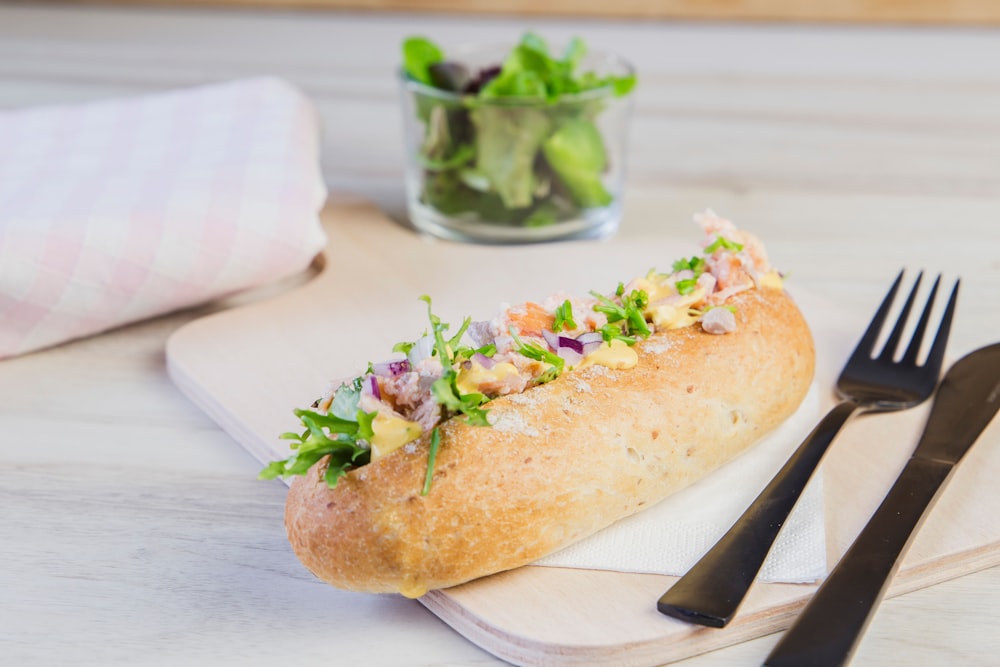 a sandwich is on a napkin next to a fork and a glass of water