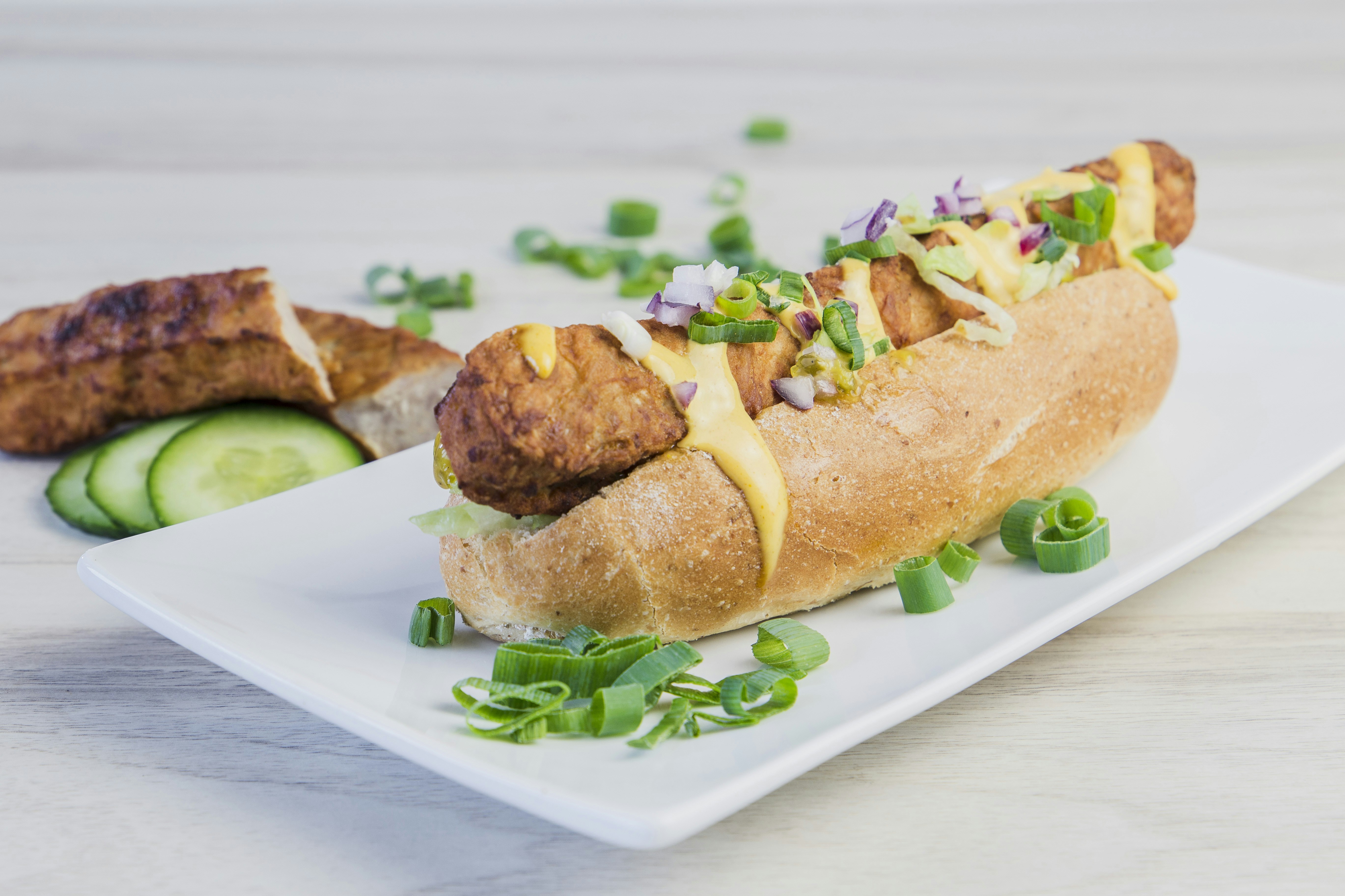 a hot dog on a bun with toppings on a plate