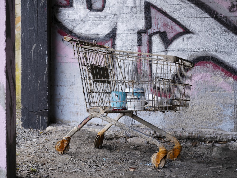 a shopping cart sitting in front of a graffiti covered wall