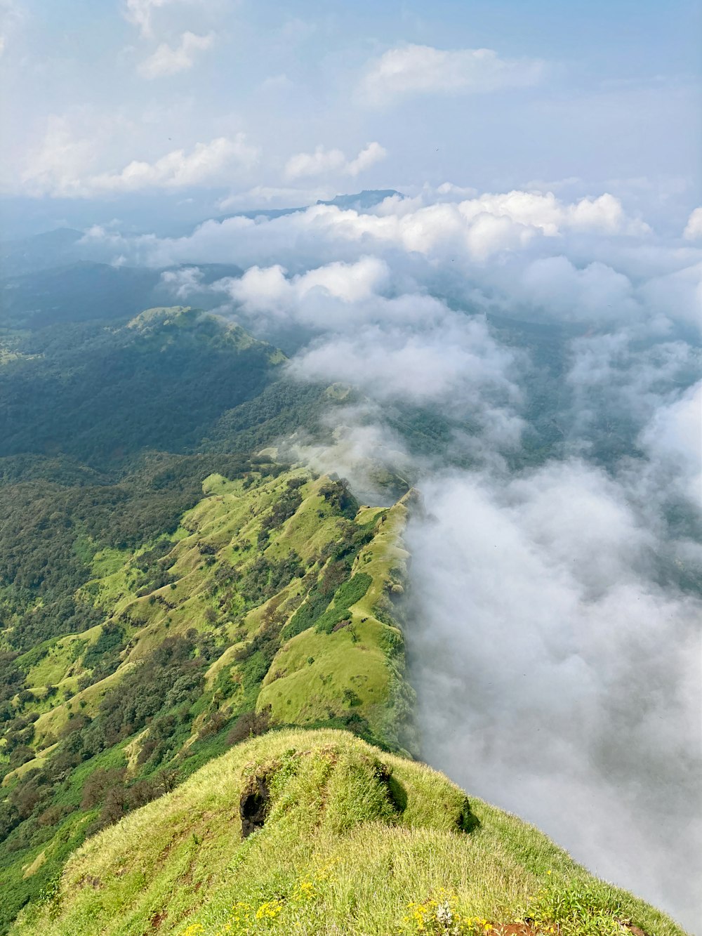 a view of a grassy hill with clouds in the sky