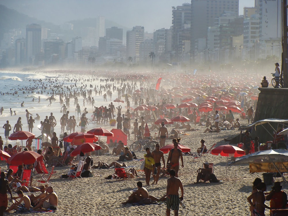 a crowded beach with many people and umbrellas