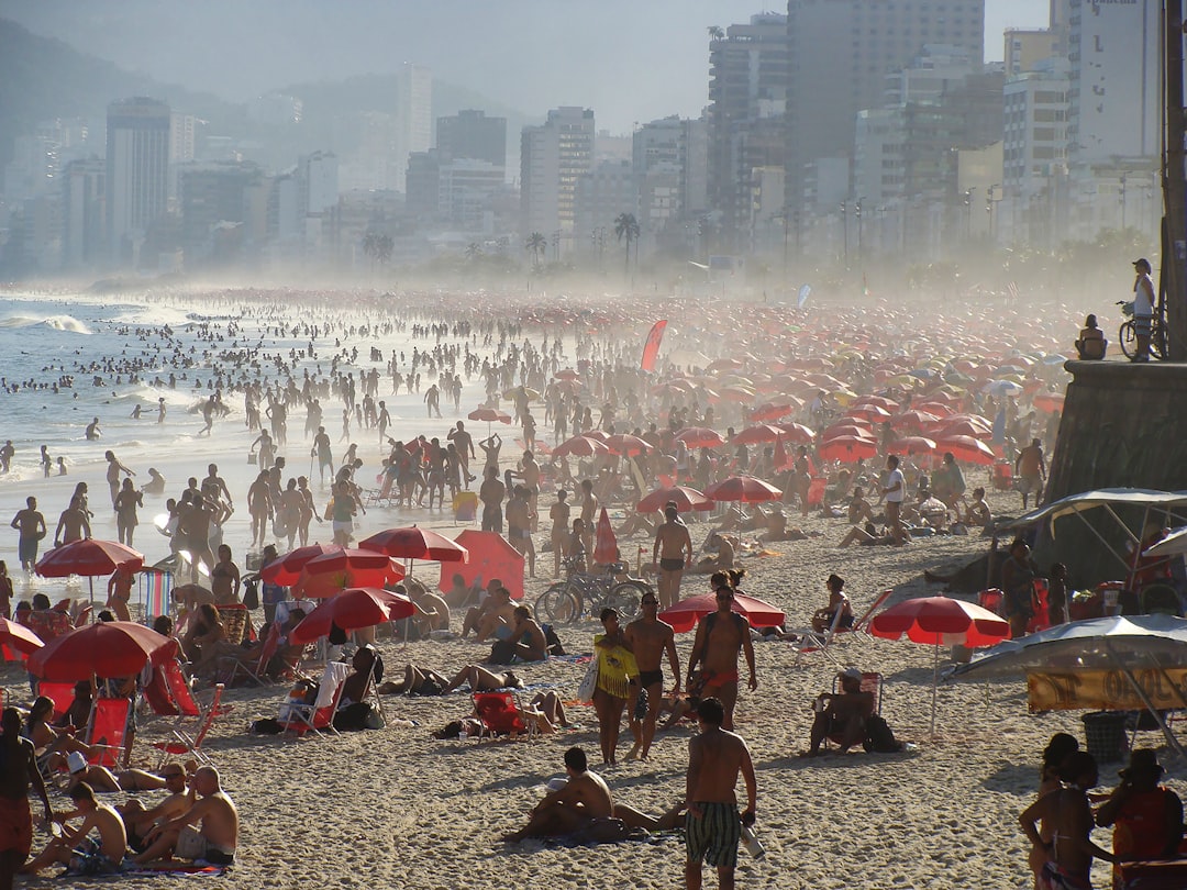 a crowded beach with many people and umbrellas,