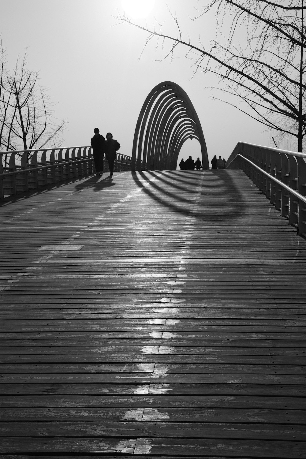 a black and white photo of people walking across a bridge