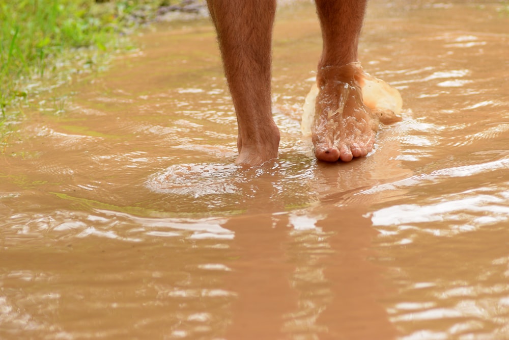 uma pessoa andando na lama com o pé na água
